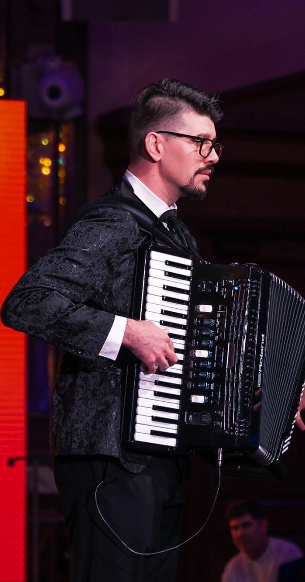 Aleksei Chebeliuk performing with the Smile Band, captivating the audience with his accordion skills and artistic stage presence.