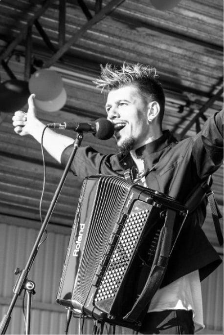Aleksei Chebeliuk performing with the Smile Band, captivating the audience with his accordion skills and artistic stage presence.